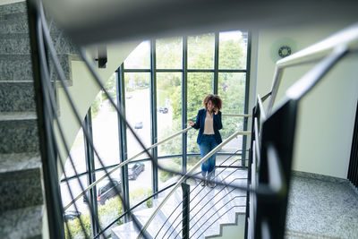 Businesswoman talking through mobile phone standing on staircase in office