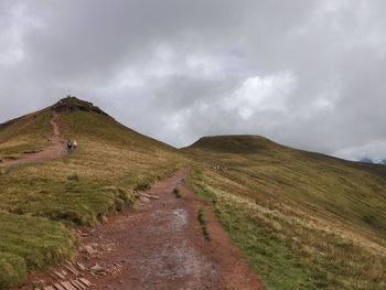 Man walking on road by mountain against sky