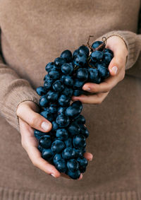 Midsection of woman holding grapes