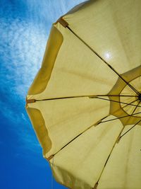 Low angle view of yellow parasol against sky