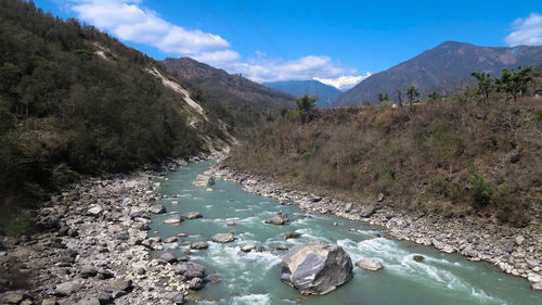 Scenic view of river amidst mountains against sky