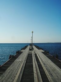 Pier over sea against clear blue sky