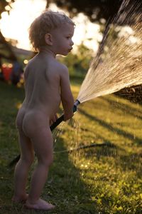 Side view of shirtless boy standing on field