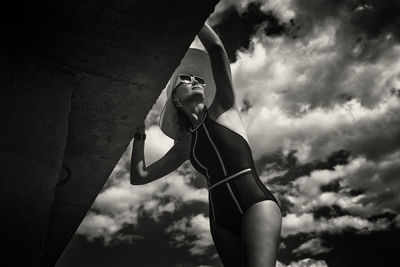 Low angle view of young woman standing against sky