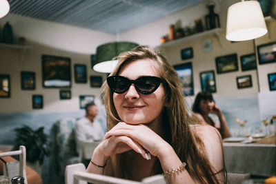 Portrait of young woman in sunglasses at cafe