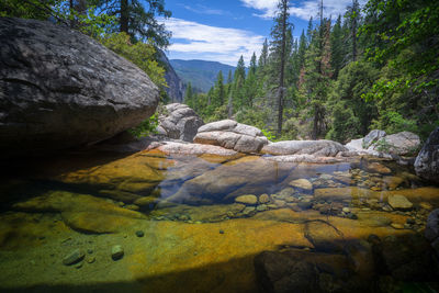 Scenic view of stream amidst rocks against sky