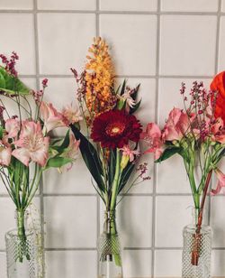 Flowers in vase by tiled wall