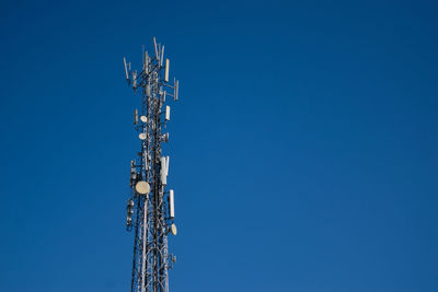 Low angle view of communications tower against blue sky