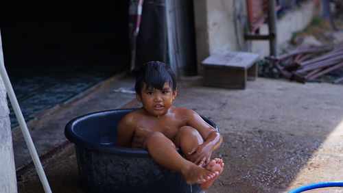 Portrait of shirtless boy sitting outdoors