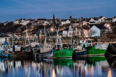 Sailboats moored in harbor by sea against sky