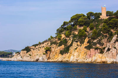 Scenic view of sea by mountain against sky