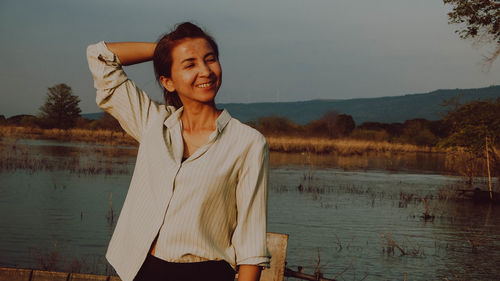 Young woman standing against lake