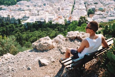 High angle view of young man sitting on bench at mountain