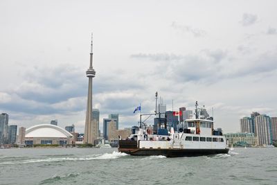 Nautical vessel on sea by city against sky