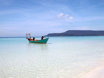 Fisherman in boat on sea against sky