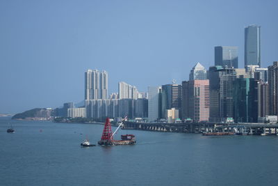 View of sea and modern buildings against clear sky