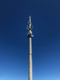 Low angle view of communications tower against clear blue sky