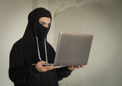 Man using mobile phone while standing against wall