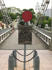 Information sign on railing in city against sky