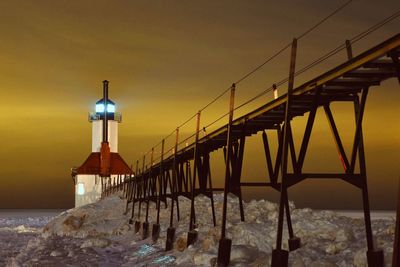 Lighthouse by sea against sky during sunset