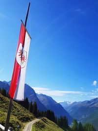 Red flag on mountain against blue sky