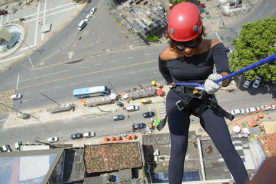 A woman wearing a hero costume with protective helmet walking down a tall rappel building. 