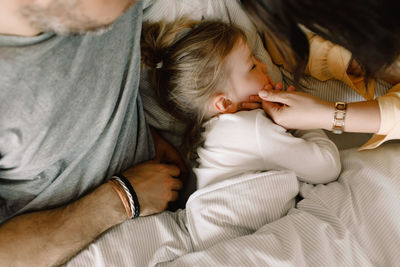 Directly above shot of girl sleeping with parents in bed at hotel