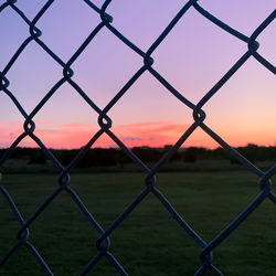 A beautiful pink sunset behind from a view behind the fence. 