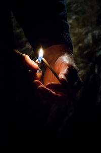 Close-up of hand holding illuminated candle