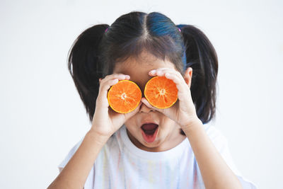 Close-up of girl holding orange over eyes