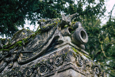 Low angle view of buddha statue against trees