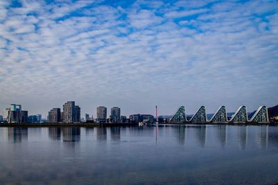 View of city by river against sky