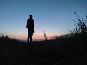 Silhouette man standing on field against sky during sunset