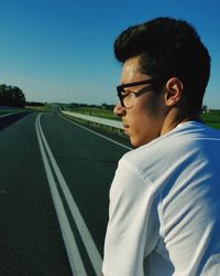 Young man wearing eyeglasses while standing on road