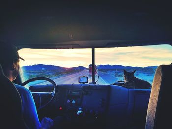 Man sitting in car against sky