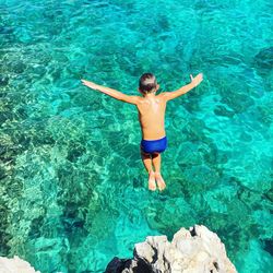 Rear view of boy jumping into water