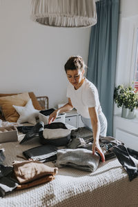 Woman folding clothes in bedroom