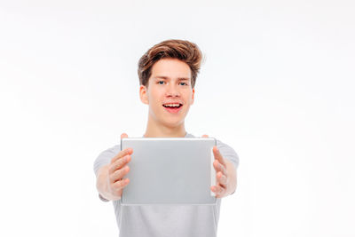 Portrait of teenage girl holding smart phone against white background