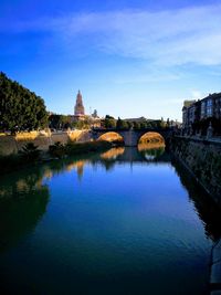 Arch bridge over river against buildings