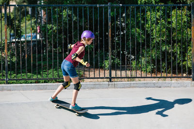 Teen skater girl skates at a skate park while wearing protective gear