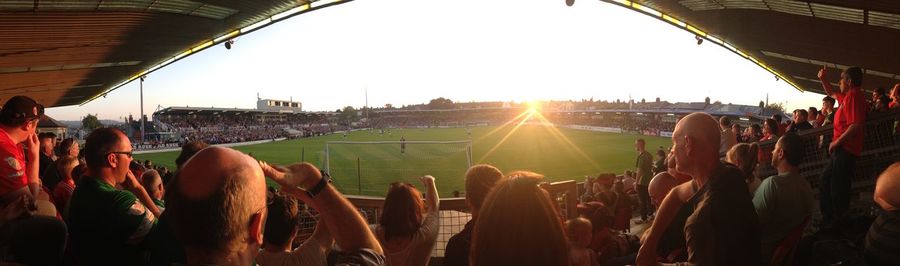 People on grassy field at sunset