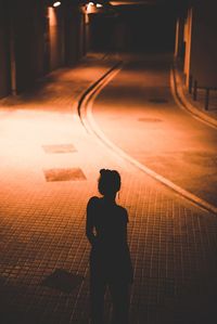 Rear view of silhouette man standing on footpath