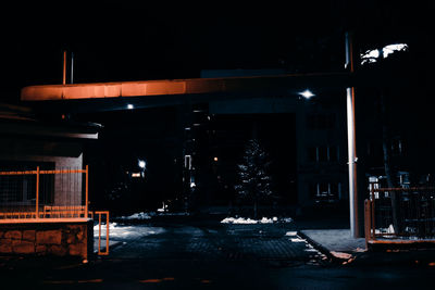 Illuminated street amidst buildings during winter at night