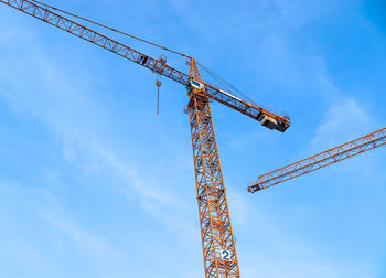 Low angle view of crane at construction site against sky