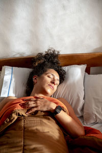 Portrait of young woman sitting on bed at home