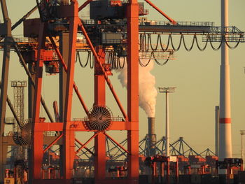 Cranes in factory against sky