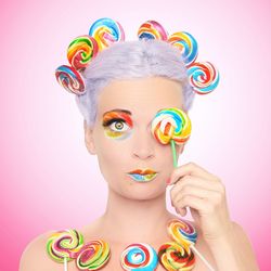 Portrait of young woman with multi colored candies against pink background