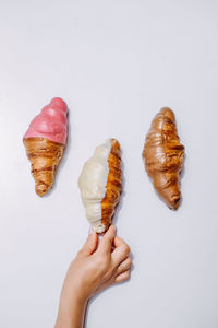 Close-up of hand holding ice cream over white background