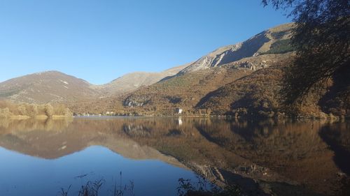 Scenic view of lake and mountains against clear blue sky