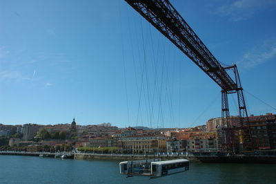 Bridge over river in city against sky